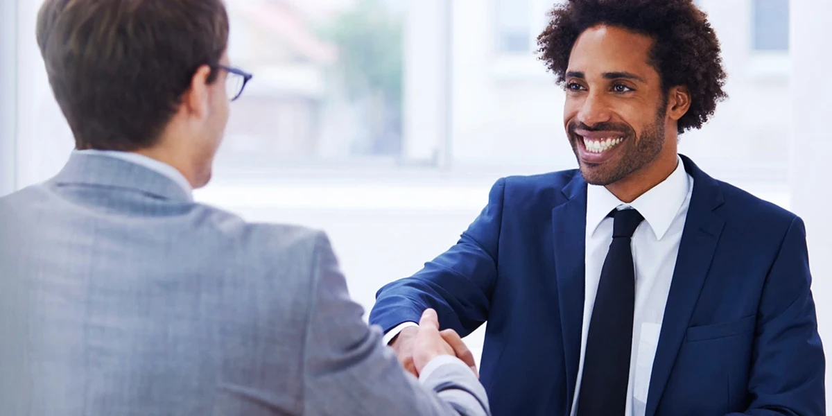 Two people in suits shake hands at an interview